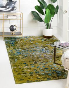 a green rug with blue flowers on it and a plant in the corner next to it