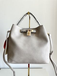 This stylish handbag is perfect for any occasion, whether you're traveling, attending a party, or simply running errands. With a rectangular shape and a light grey exterior color, it's both classic and versatile. The bag features a button and clasp closure, a crossbody strap, and a detachable strap for added convenience. Inside, you'll find cotton lining and several inner pockets to keep your belongings organized. The faux leather exterior material is accented with a button accent and gold-plated hardware for a touch of sophistication. This medium-sized bucket handbag is suitable for women and is 9 inches wide, 8 inches tall, and 5 inches deep. No matter where you're headed, this purse will be the perfect accessory to complete your outfit. Gray Crossbody Shoulder Bag For Daily Use, Gray Shoulder Bag With Removable Pouch, Gray Large Capacity Top Handle Shoulder Bag, Gray Tote Shoulder Bag With Adjustable Strap, Gray Rectangular Hobo Bag For Daily Use, Rectangular Gray Hobo Bag For Daily Use, Gray Shoulder Bag With Adjustable Strap For Shopping, Gray Shoulder Bag With Adjustable Strap And Double Handle, Trendy Gray Satchel For Shopping