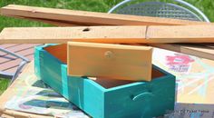 an open wooden box sitting on top of a table next to a green planter