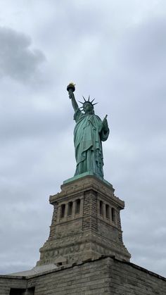 the statue of liberty is shown against a cloudy sky