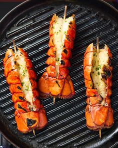 four lobsters are cooking on the grill with cheese and parmesan toppings