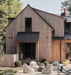 an outdoor patio with chairs and potted plants in front of a barn style house