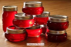 several jars filled with red liquid sitting on top of a wooden table