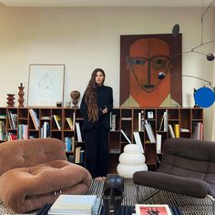 a woman standing in front of a living room filled with furniture and bookshelves