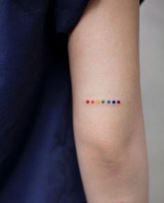 a woman's arm with a small rainbow tattoo on the left side of her arm