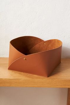 two brown leather containers sitting on top of a wooden table next to a white wall