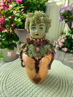 there is a small doll sitting in a potted plant