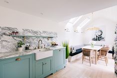 a kitchen with green cabinets and marble counter tops, along with a dining room table