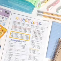 an open notebook sitting on top of a table next to some pens and pencils