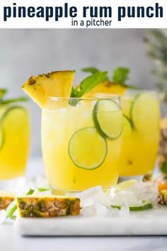 pineapple rum punch in a pitcher garnished with cucumber and mint