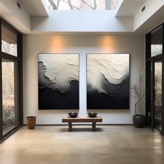 two black and white paintings on the wall in a room with large glass doors leading to an outside patio