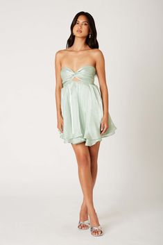 Baby, You're a Doll in this sleek and shiny mini dress! With a sweetheart neckline, flattering babydoll silhouette, and tiered ruffle skirt, this cocktail-ready mini is as fun to wear as the event you're attending. Topped off with an elastic strap at the back and a precious bow detail. Runs true to size ~ model wearing size extra small Shell: 100% Polyester; Lining: 95% Polyester, 5% Spandex Fully lined Front twist detail with cutout Tie back Layered Ruffle Dress Formal, Ruffle Dress Formal, Turquoise Mini Dress, Strapless Dresses Short, Green Cocktail Dress, Dress And Jacket Set, Tiered Ruffle Skirt, Hoco Dresses, Layered Skirt