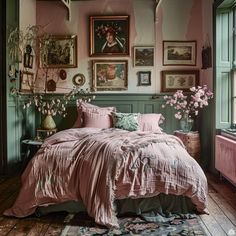 a bed with pink sheets and pillows in a room filled with pictures on the wall