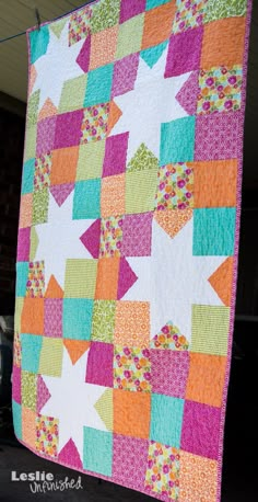 a colorful quilt hanging from the side of a building