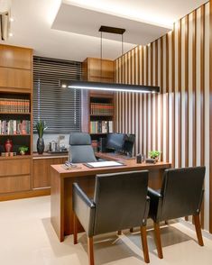 an office with two leather chairs and a wooden desk in front of a bookshelf