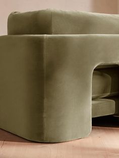 a green couch sitting on top of a wooden floor