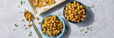 two blue bowls filled with corn on top of a white surface next to a spoon