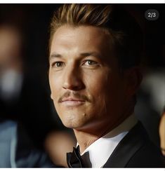 a close up of a person wearing a tuxedo and looking at the camera