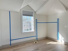 an empty room with white walls and blue tape on the wall, along with a window