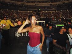 a woman in a red top is talking on her cell phone at a concert with other people