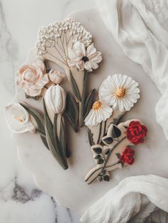 some flowers are laying on top of a marble slab with white and red flowers in the middle