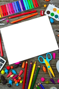 an assortment of arts and crafts supplies on a wooden table with a blank paper surrounded by crayons