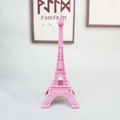 a pink plastic model of the eiffel tower in front of a white wall