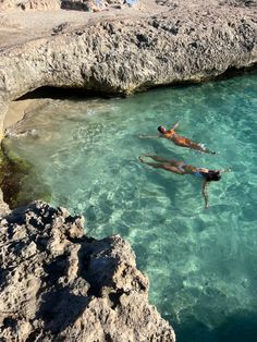 two people are swimming in the clear blue water