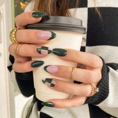 a woman holding a coffee cup with green and pink manies on her nails, while wearing