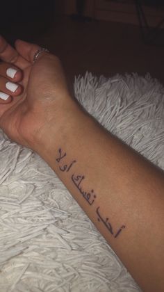 a woman's arm with arabic writing on it and her hand holding the wrist