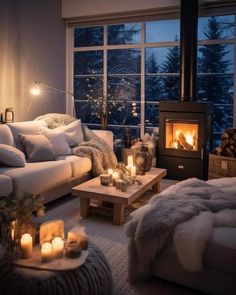 a living room filled with furniture and a fire place next to a large window at night