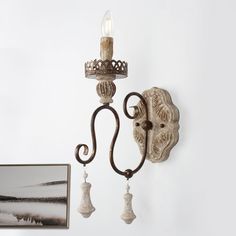 a wall mounted light with two candles on it and a painting hanging next to it