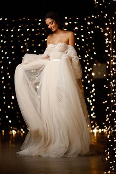 a woman in a white dress with lights behind her