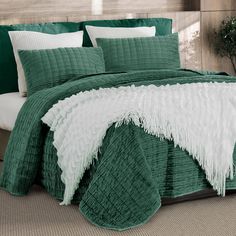 a green bed with white pillows and blankets