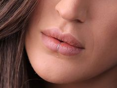 a close up shot of a woman's face with her nose ring in the middle