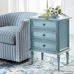 a blue striped chair sitting next to a small table with flowers on top of it