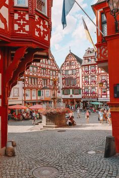 people are walking around in an old town with red and white buildings on either side