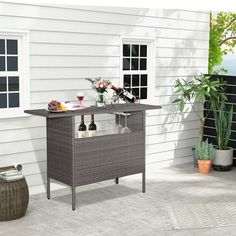 an outdoor bar with wine glasses and bottles on the table next to a potted plant