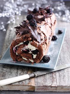 a piece of chocolate cake on a plate with blackberries and whipped cream around it