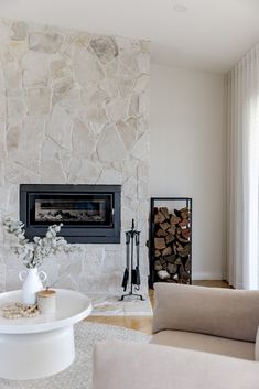 a living room filled with furniture and a fire place in front of a stone wall