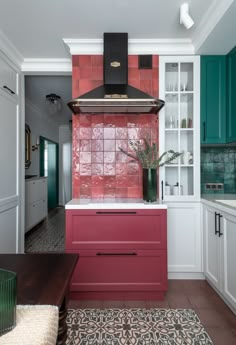 a kitchen with red and green tiles on the wall, cabinets and stove top oven