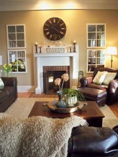 a living room filled with furniture and a clock on the wall above it's fireplace