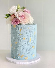 a blue cake with pink and white flowers on top