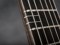 an acoustic guitar neck with strings and knobs on the fret end, close up