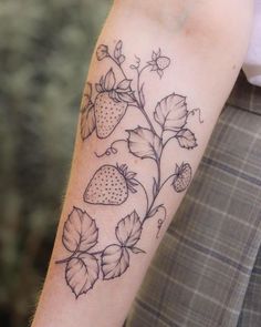 a tattoo on the arm of a man with strawberries and leaves growing out of it