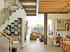 a living room filled with lots of furniture and bookshelves next to a stair case