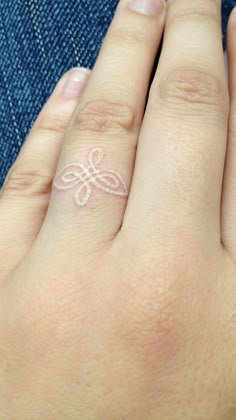 a woman's hand with a small tattoo on her left ring and the word love written in white ink