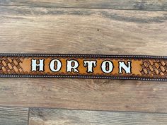 a belt with the word horton on it sitting on top of a wooden floor next to a wall