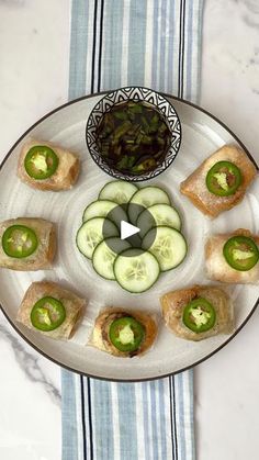 a plate with cucumbers and green peppers on it next to a bowl of pickles