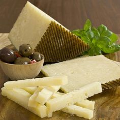 several different types of cheese on a cutting board with olives and parmesan cheese